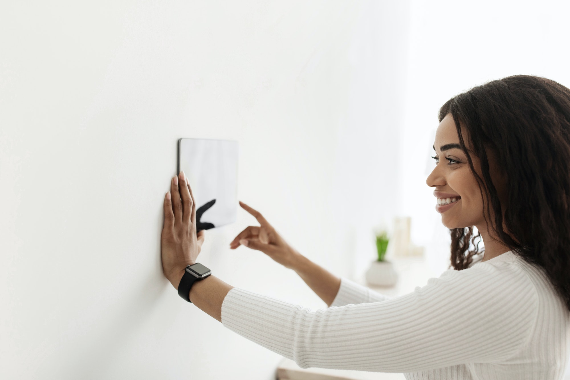 African american woman using digital tablet with blank screen on wall with smart home control system